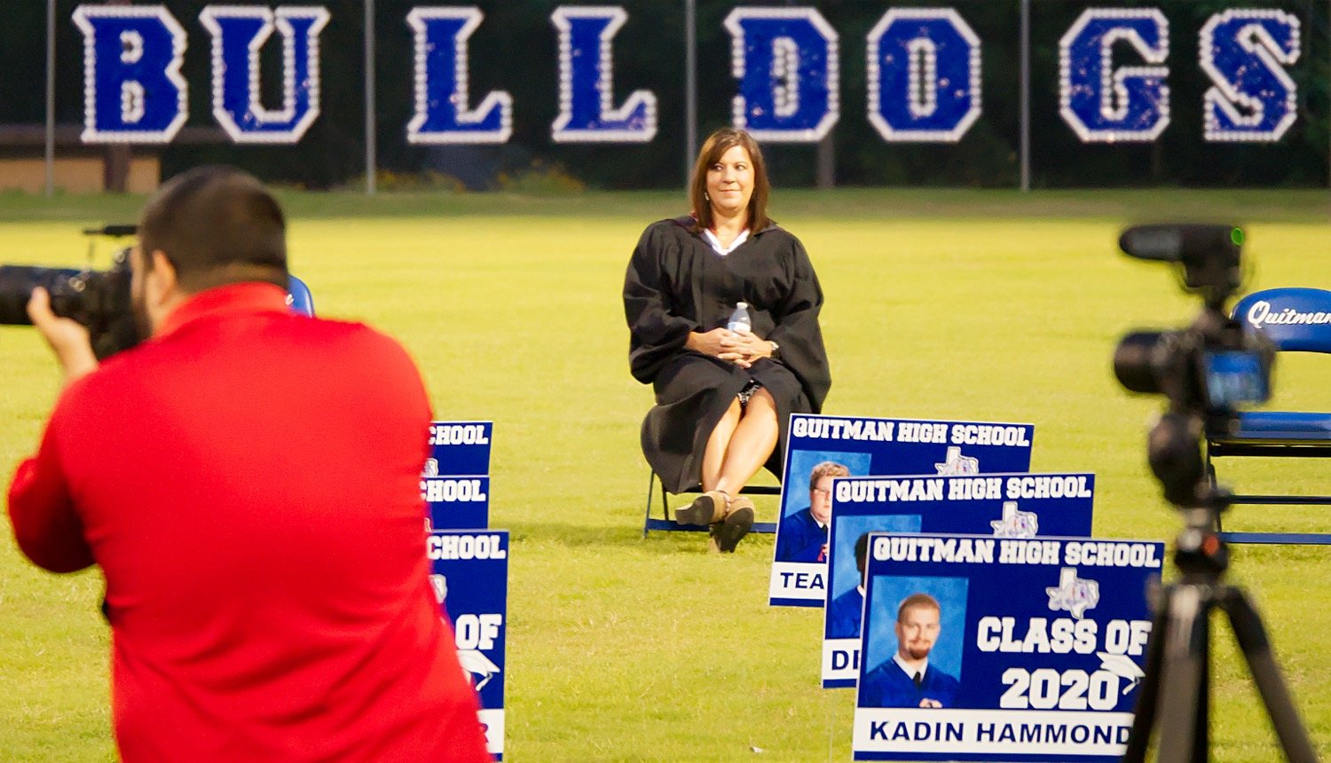 Quitman High School Principal Dana Hamrick takes a break from announcing graduates as photographer Chad Parish shoots the virtual graduation Monday night at Bud Moody Stadium. Parish plans to edit the individual videos into a virtual graduation which will be shown by the school district at 7 p.m. on Friday, May 22, which was to be the time for the actual graduation.